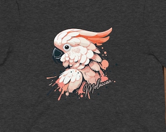May include: A dark heather grey t-shirt with a pink and white cockatoo illustration. The cockatoo is surrounded by pink paint splatters. The text "Moluccan" is written in white below the cockatoo.