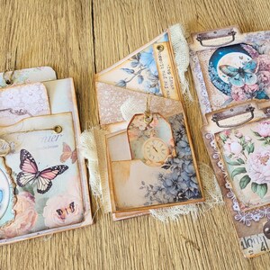 K&ouml;nnte beinhalten: Ein Set aus vier dekorativen Scrapbook-Papierseiten mit Blumen- und Schmetterlingsmotiven. Die Seiten sind mit Spitze, B&auml;ndern und Verzierungen verziert. Die Seiten sind in den Farben Rosa, Blau und Gr&uuml;n gehalten.