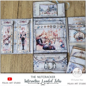 Op de afbeelding: Een interactief, geladen folio met een notenkrakerthema in een blauw-wit kleurenschema. Het folio heeft een verscheidenheid aan zakken en compartimenten, waaronder een zak met het label "Candy Canes" en een andere met het label "Sugarplum". Het folio is versierd met afbeeldingen van de notenkraker, een kasteel en een wintersc&egrave;ne.