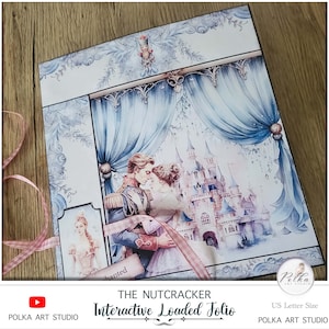 Op de afbeelding: Een blauw en wit interactief geladen folio met een aquarel-illustratie van een dansend stel voor een kasteel. Het folio is getiteld "The Nutcracker Interactive Loaded Folio" en is gelabeld "US Letter Size".