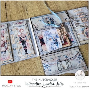 Op de afbeelding: Een blauwe en witte interactieve geladen folio met de titel "The Nutcracker Interactive Loaded Folio" en de tekst "Candy Canes" en "Sugarplum".