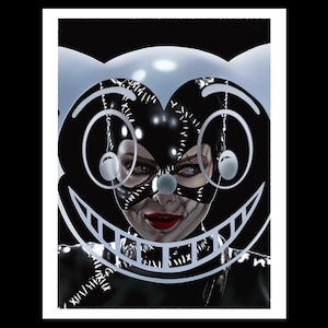 May include: A black and white illustration of a woman wearing a cat mask with a large, cartoon-style, smiling face superimposed over her. The woman's eyes are visible through the mask.
