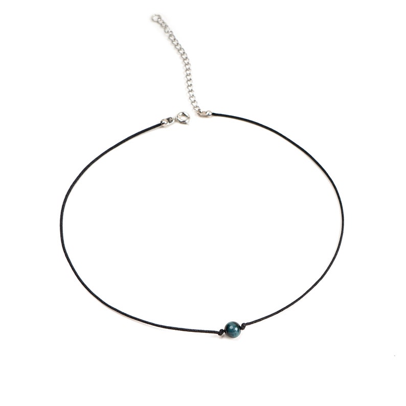 May include: A simple black cord necklace with a single dark green gemstone bead.