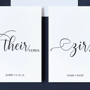 May include: Two white cards with black calligraphy. The top card says "their vows" and the bottom card says "Jamie 5-22-21". The second card says "our vows" and the bottom card says "NAME DATE".