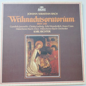 May include: A vintage vinyl record album featuring Johann Sebastian Bach's Weihnachtsoratorium. The album cover is a mix of brown and white, with text in German and an illustration of a religious scene. The album is from the Archiv Produktion label.