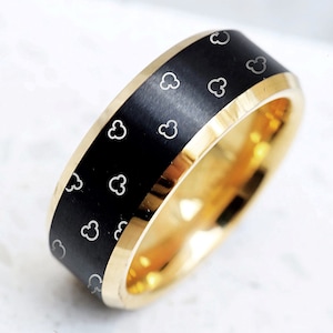 May include: A black and gold wedding band with a brushed finish and a pattern of small white Mickey Mouse heads.