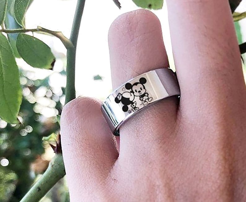 May include: A silver ring with a black and white image of Mickey Mouse and Minnie Mouse holding hands.