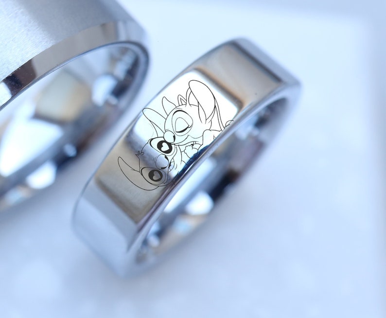 May include: Two silver wedding bands with a laser engraved image of Stitch and Angel from the Disney movie Lilo & Stitch.