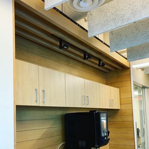 May include: A wall with wood paneling and a set of cabinets with silver handles. A black coffee maker with the word "Melitta" on it is in the lower right corner of the image.