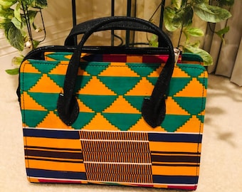 May include: A black and green patterned handbag with a black zipper and handles. The bag has a geometric design with yellow, green, brown, and blue colours.
