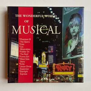 Puede incluir: Una portada de libro roja y blanca con el título "The Wonderful World of Musical" y una lista de musicales populares, incluyendo "Phantom of the Opera", "Cats", "Les Miserables", "Fiddler on the Roof", "West Side Story", "Funny Girl", "Evita", "Jesus Christ Superstar" y "Starlight Express". La portada presenta una foto de una calle de la ciudad por la noche con un gran letrero de neón que dice "ROXY".