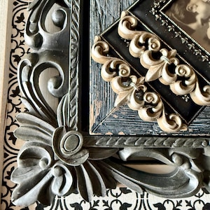 May include: Close-up of ornate picture frames. The frames are in various styles, including a dark gray, heavily carved frame with floral details and a black frame with gold accents. The background features a black and white patterned design.