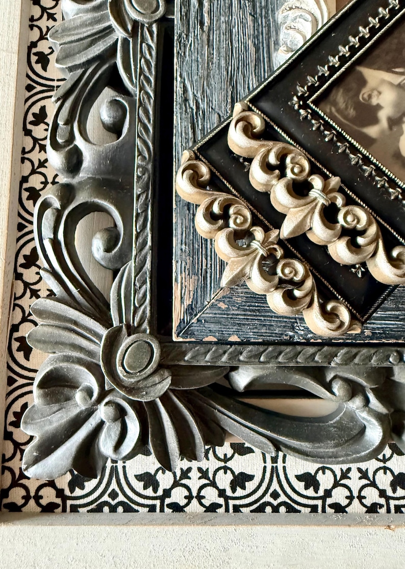 May include: Close-up of ornate picture frames. The frames are in various styles, including a dark gray, heavily carved frame with floral details and a black frame with gold accents. The background features a black and white patterned design.