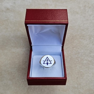 Può includere: Un anello d'argento con una pietra ovale bianca con un design geometrico blu e bianco all'interno di una scatola per anelli in velluto rosso.