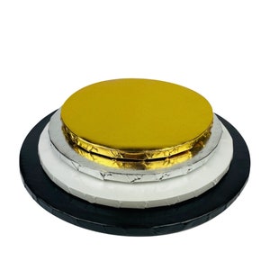 May include: Three round cake boards stacked on top of each other. The top board is gold, the middle board is silver, and the bottom board is black.