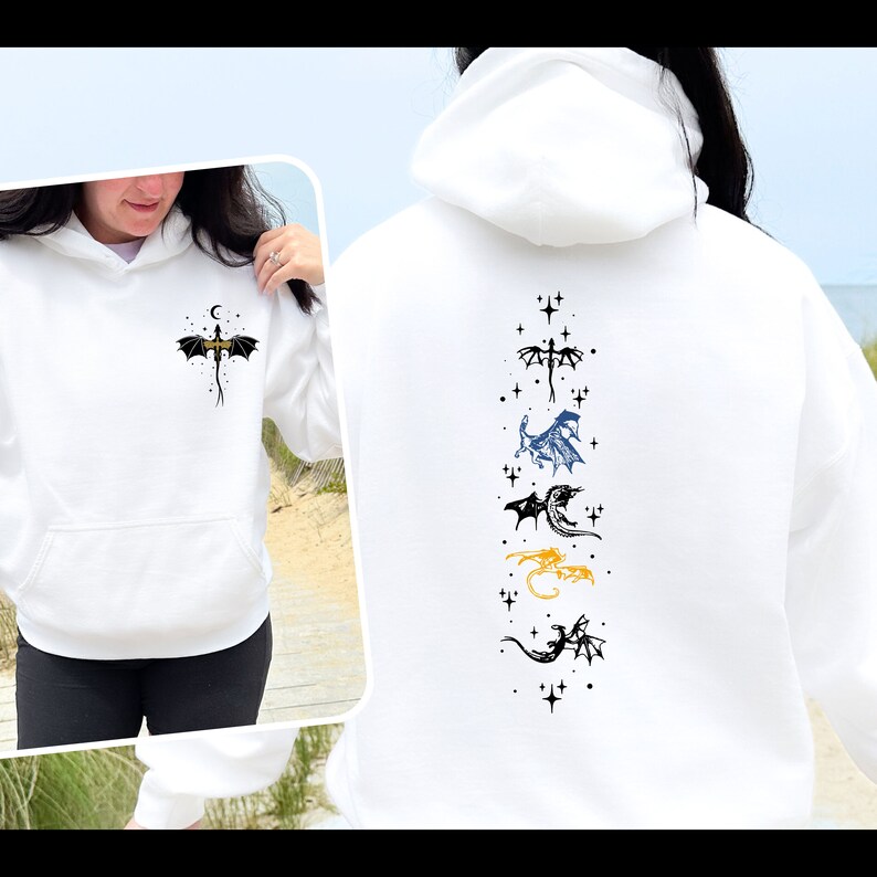 May include: White hooded sweatshirt featuring a dragon design. The front displays a small dragon with a crescent moon and stars. The back showcases a vertical arrangement of various dragon illustrations in black, blue, and gold.