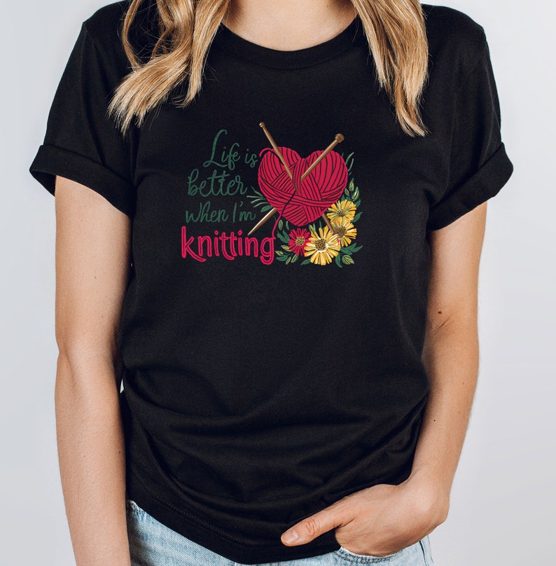 May include: Black t-shirt with the text "Life is better when I'm knitting" and a red yarn ball with knitting needles and flowers.