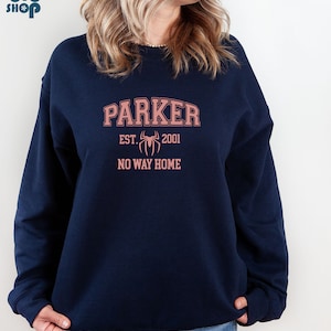 May include: A navy blue sweatshirt with a pink graphic design. The graphic features the text "Parker" in an arched font, "EST. 2001" below, a stylized spider, and the text "NO WAY HOME".