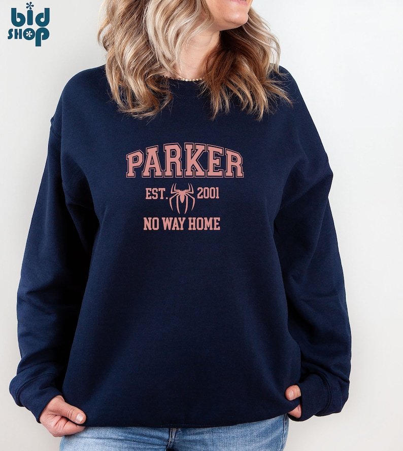 May include: A navy blue sweatshirt with a pink graphic design. The graphic features the text "Parker" in an arched font, "EST. 2001" below, a stylized spider, and the text "NO WAY HOME".