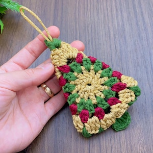 Peut inclure: Une décoration de Noël en forme d'arbre de Noël en crochet de couleur or, vert et rouge. L'ornement est en forme d'arbre de Noël traditionnel et a une boucle en haut pour l'accrocher.