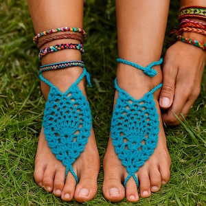 May include: A pair of turquoise crochet barefoot sandals with a fan-like design. The sandals are connected by a toe loop and ankle ties. The image also shows multiple colorful bracelets on the ankles and wrists.