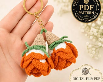 Peut inclure: Un porte-clés rose au crochet composé de deux fleurs orange et blanches avec des centres beige et des tiges vertes fixées à un anneau en métal doré. L'image contient le texte Crochet Rose Keychain PDF Pattern Instant Download.