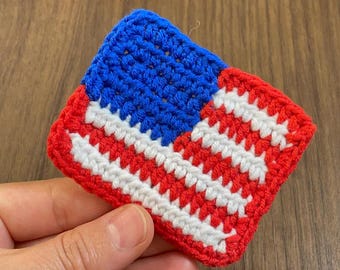 May include: A small crocheted American flag in red, white, and blue.