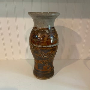 May include: A brown and white ceramic vase with a geometric pattern. The vase has a wide mouth and a narrow base.