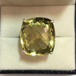 May include: A large, cushion-cut, yellow citrine gemstone ring set in a silver band.