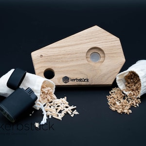May include: A wooden fire starter kit with a small wooden tray, two white fabric bags filled with wood shavings, and a black fire starter. The tray has a hole in the center and the text "kerbstück" is printed on the bottom right corner.