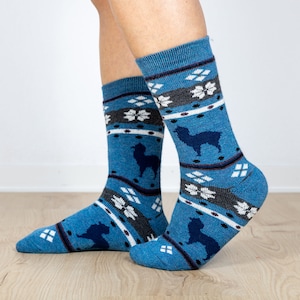 Pu&ograve; includere: Un paio di calzini blu con un motivo bianco e grigio con alpaca. I calzini sono realizzati in un materiale morbido e confortevole.