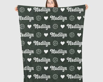 May include: A dark green fleece blanket with a white volleyball and heart pattern. The name "Madilyn" is repeated throughout the blanket.