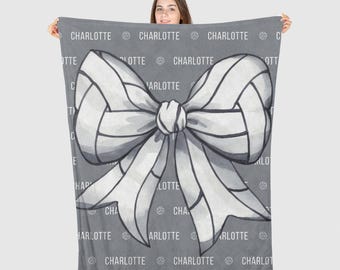 May include: Grey and white throw blanket with a large white bow and the word "CHARLOTTE" repeated throughout the design.