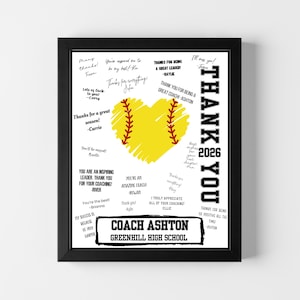 May include: A framed print with a black border. The artwork features a yellow softball heart with red stitching, surrounded by handwritten thank you messages. The words "THANK YOU" are vertically aligned on the right side, with "2026" below. The bottom reads "COACH ASHTON GREENHILL HIGH SCHOOL."