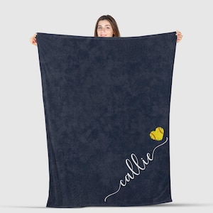 May include: A navy blue fleece blanket with a yellow softball heart and the name "callie" written in white cursive.