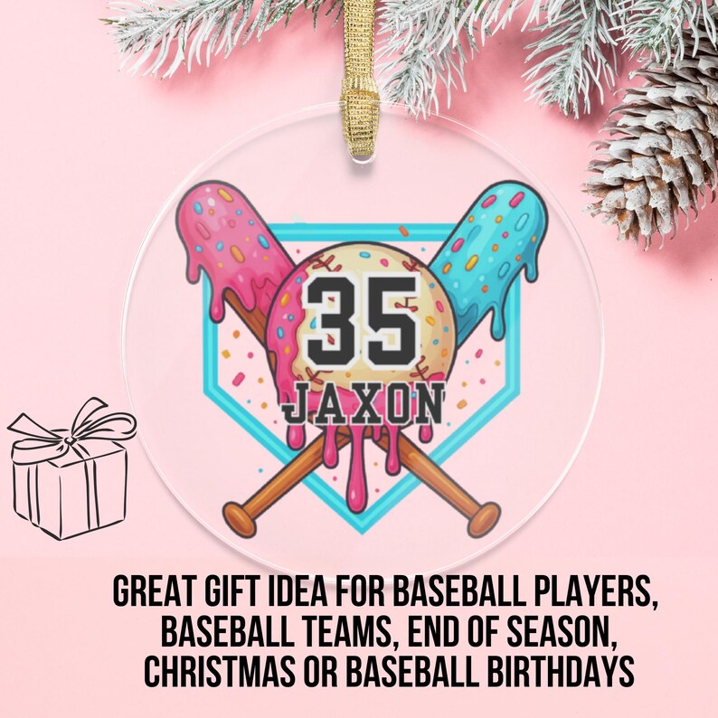 May include: A clear, round ornament with a baseball theme. It features a baseball diamond design with crossed bats and the number 35. The name "Jaxon" is below the number. The ornament has a gold ribbon for hanging.