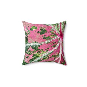 May include: Square throw pillow with a vibrant leaf pattern. The pillow features a close-up of a leaf with pink, green, and white hues. The leaf's veins are visible, creating a textured appearance. The pillow is a decorative item for home decor.