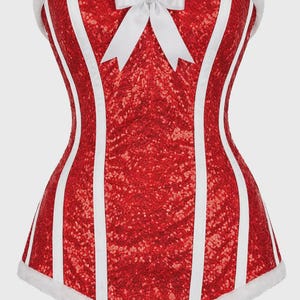 May include: A red sequinned corset featuring vertical white stripes, a white satin bow at the centre neckline, and white faux fur trim along the top and bottom edges. The garment has a sweetheart neckline and a structured, fitted silhouette.