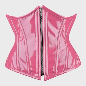 May include: A bright pink corset with a glossy, patent-like finish. The garment features a central silver-toned metal zipper closure running vertically from the top to the bottom, with structured vertical seams throughout the front panel design.