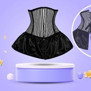 May include: A black and white striped corset with a black satin skirt. The corset has a lace-up back and is displayed on a purple pedestal.