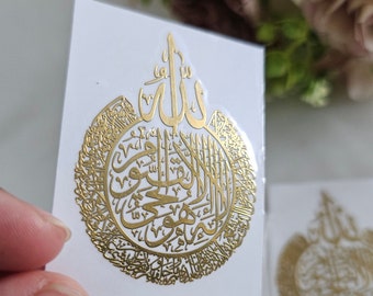 May include: Gold temporary tattoo with Arabic calligraphy in a circle. The calligraphy reads "Allah" in the center and is surrounded by other Arabic text.