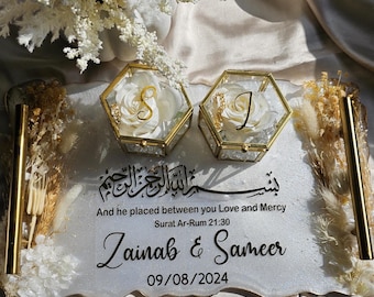 May include: A white tray with gold accents and a gold handle. The tray has two glass boxes with white roses and gold letters inside. The tray also has the text "And he placed between you Love and Mercy Surat Ar-Rum 21:30 Zainab & Sameer 09/08/2024" written on it.