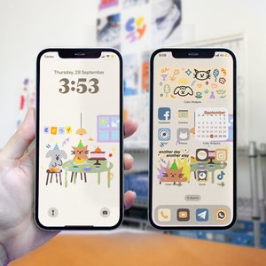 Könnte beinhalten: Ein Screenshot eines iPhones, der einen benutzerdefinierten Startbildschirm mit bunten Widgets und Symbolen anzeigt. Die Widgets umfassen einen Kalender, eine Uhr und Social-Media-Apps. Die Symbole sind für Apps wie Facebook, Instagram, Spotify und TikTok. Der Hintergrund ist hellbeige mit einer Comic-Katze und einem Comic-Hund, die Partyhüte tragen.