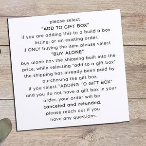 May include: A white paper with text explaining how to select gift box options. The text includes instructions on choosing "ADD TO GIFT BOX" or "BUY ALONE". A logo with the text "PICTURE PERFECT SERIES" is in the upper right corner.
