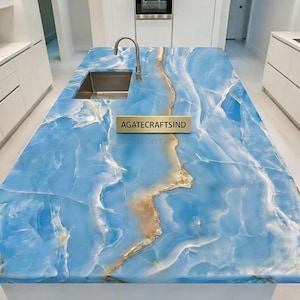 May include: A blue and gold countertop with a stainless steel sink and faucet. The countertop has a marbled appearance with the text "AGATECRAFTSIND" on a gold plate.