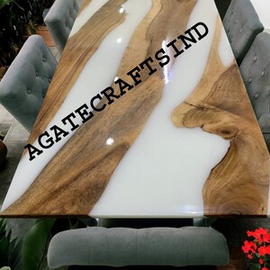 May include: A white and brown epoxy resin dining table with a live edge design. The table is surrounded by gray chairs and has the text "AGATECRAFTSIND" printed on the surface.