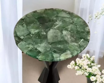 Puede incluir: Una mesa redonda verde con una tapa única de mosaico hecha de piezas de piedra verde. La mesa tiene una base negra de trípode.