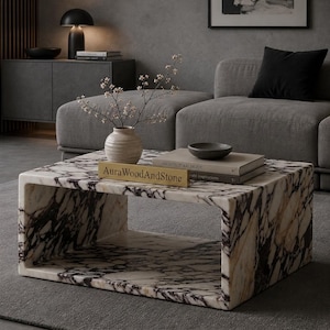 May include: A rectangular coffee table crafted from white marble with prominent dark purple and black veining. The table features a hollow, open-center design. A gold-toned rectangular plaque with the text AuraWoodAndStone sits on top.