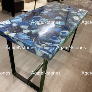May include: A blue agate table top with a black metal frame. The table top is made of polished agate stone with a variety of blue and white patterns. The table is a unique and stylish piece of furniture that would add a touch of elegance to any home.