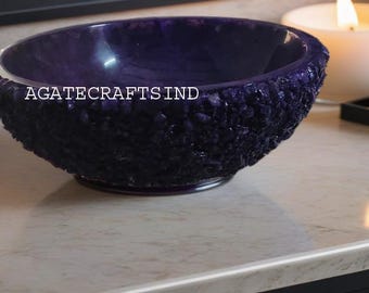 May include: A deep purple agate bowl with a textured surface. The bowl is made of natural stone and has a unique, organic shape. The bowl is perfect for holding jewelry, trinkets, or other small items. The bowl is also a beautiful decorative piece for any home.